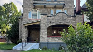 A two-story stone house with a garage, a front porch, and a chimney. - Cozy Mother-In-Law Suite (Pittsburgh)