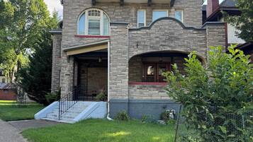 A two-story stone house with a garage, a front porch, and a chimney.