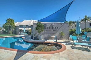En swimmingpool med parasol, liggestole og et skilt med teksten "The Nautilus".