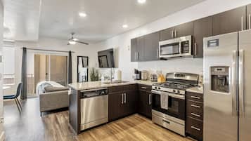 A modern kitchen with stainless steel appliances, dark wooden cabinets, and a granite countertop.