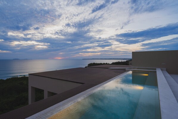 Une piscine avec vue sur la mer et un ciel nuageux.