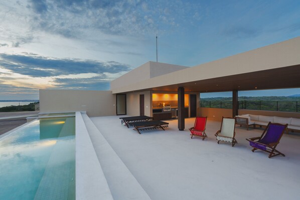A modern outdoor pool area with lounge chairs and a view of the landscape. - Penthouse Arenamar in Punta Mita (Punta de Mita)