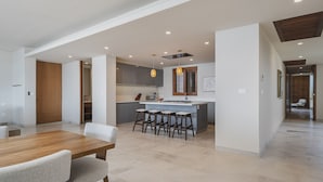 A modern kitchen with a central island, bar stools, and pendant lighting. - Penthouse Arenamar in Punta Mita (Punta de Mita)