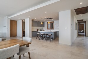 Una cocina moderna con una isla central, taburetes de bar e iluminación colgante.