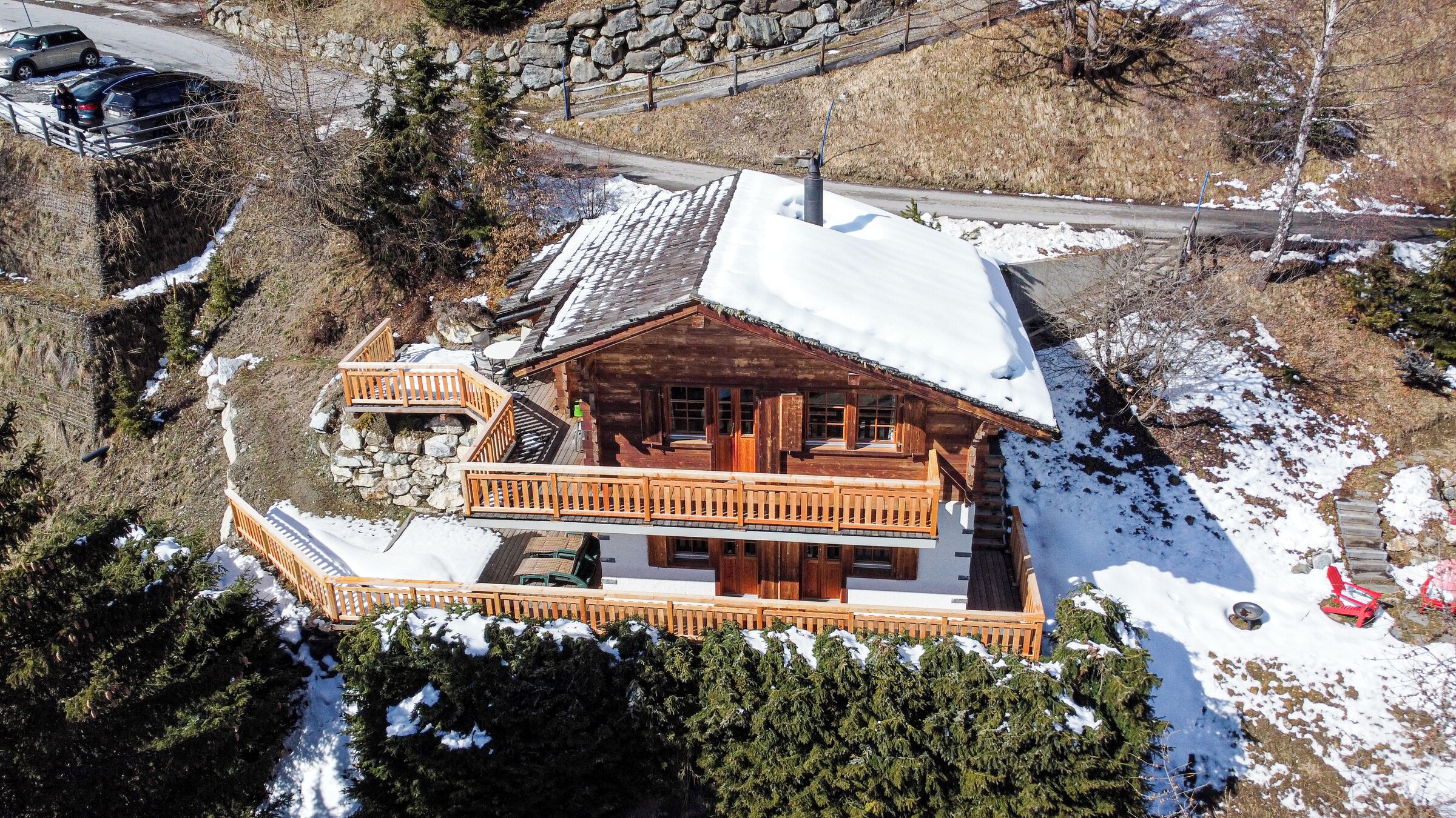A wooden cabin with a balcony, surrounded by snow and trees.