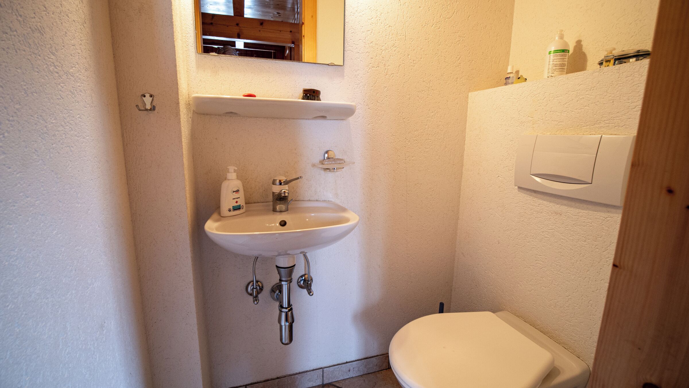 Ein kleines Badezimmer mit einem weißen Waschbecken, einer Toilette und einem Spiegel über dem Waschbecken.