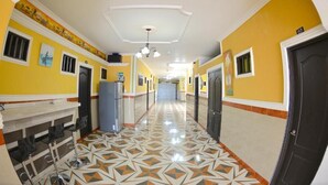 Un long couloir aux murs jaunes, doté d’un sol à motifs et d’un plafond pourvu d’un éclairage encastré.