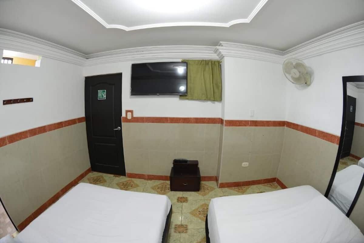 Une chambre d’hôtel avec deux lits, un téléviseur à écran plat, une porte et une petite table.
