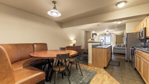Een moderne keuken met houten kastjes, een centraal eiland en een zithoek met een bruine leren bank en stoelen.