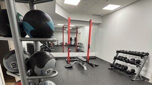 A gym with weightlifting equipment, including dumbbells and medicine balls, and a bench. - 12th Floor Studio at Downtown.  Parking Included (Edmonton)