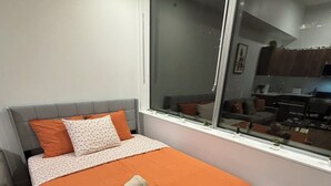 A bedroom with a bed, pillows, a window, and a view of a kitchen. - 12th Floor Studio at Downtown.  Parking Included (Edmonton)