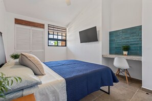 A bedroom with a bed, a desk, a TV, and a window with blinds. - Cozy Nice apartment in the best location (Puerto Vallarta)