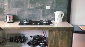 Una cocina con estufa a gas, un hervidor y diversos utensilios de cocina.