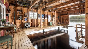 Une cabane en bois dotée d’une grande terrasse en bois, d’un bain à remous et offrant une vue sur un lac.