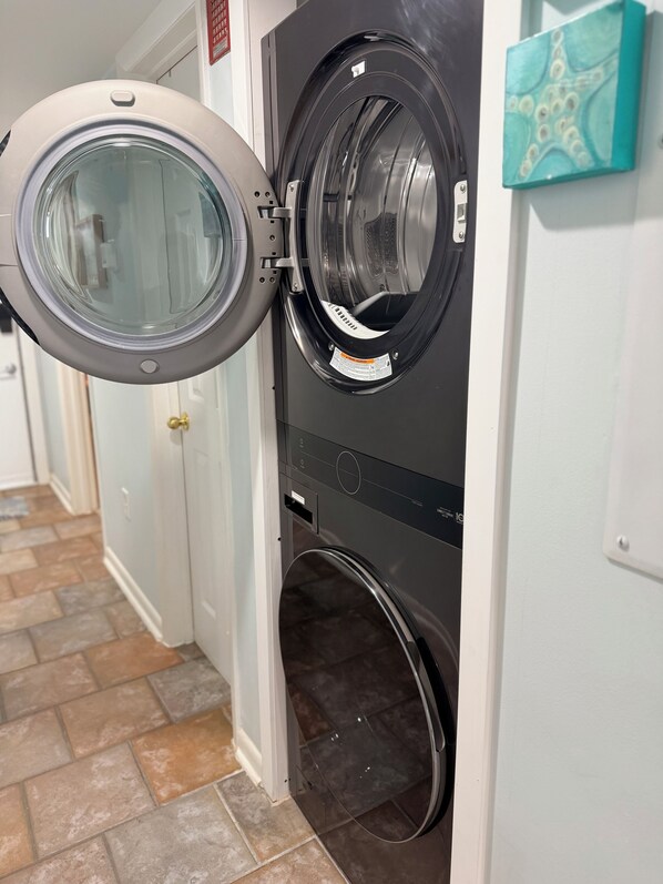 A laundry room with two front-loading washing machines and a door. - Oceanfront Getaway with Stunning Views , Pool, & Easy Beach Access (North Myrtle Beach)