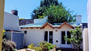 A small, single-story house with a sloped roof and a small porch. - Splendid house, very bright, 3 bedrooms, 3 bathrooms, kitchen, barbecue. Courtyard (Chascomús)