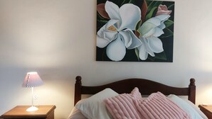 A bedroom with a bed, two bedside tables, a nightstand, a lamp, a pillow, a blanket, and a wall-mounted painting. - Splendid house, very bright, 3 bedrooms, 3 bathrooms, kitchen, barbecue. Courtyard (Chascomús)
