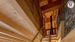 A wooden staircase leading to a loft bedroom with a stone wall and a cozy living area below. - La Liete - 1st Floor (BESSANS)