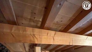 A wooden loft bedroom with a sloped ceiling, a stone wall, and a bed with a blue cover. - La Liete - 1st Floor (BESSANS)