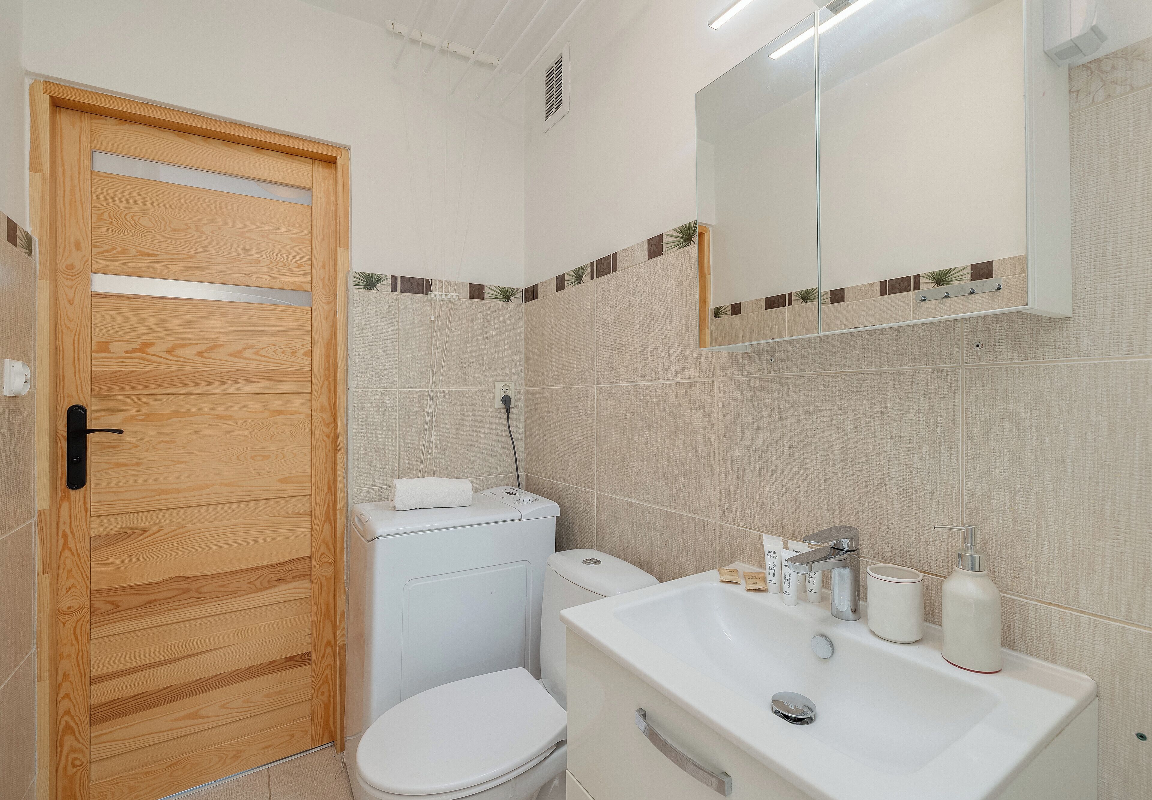 A bathroom with a wooden door, white toilet, and sink with toiletries.
