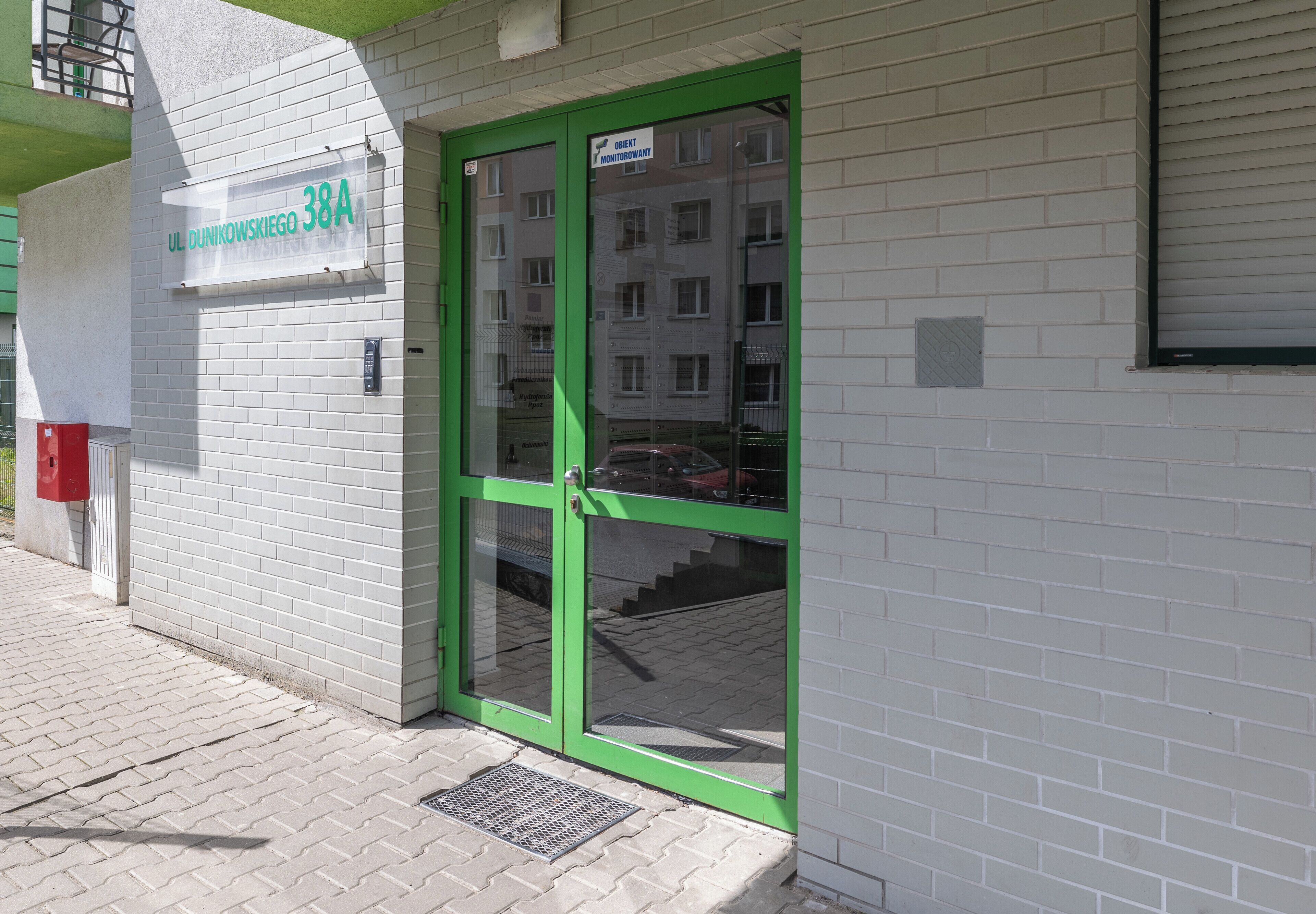 A building with a green door and a sign that reads "UL DUNKOWSKIEGO 38A".