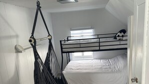 A compact room with a bunk bed, a hammock, a window, and a door.