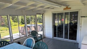 A covered patio area with a table and chairs, a sliding glass door leading outside, and a view of the outdoors.