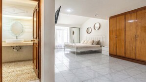 A bedroom with a bed, a wardrobe, and a bathroom with a sink and mirror. - Family Home with Heated Pool (Guadalajara)