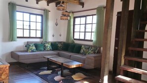 Un salon chaleureux avec un plafond en bois, un ensemble de canapés, une table basse et un escalier.