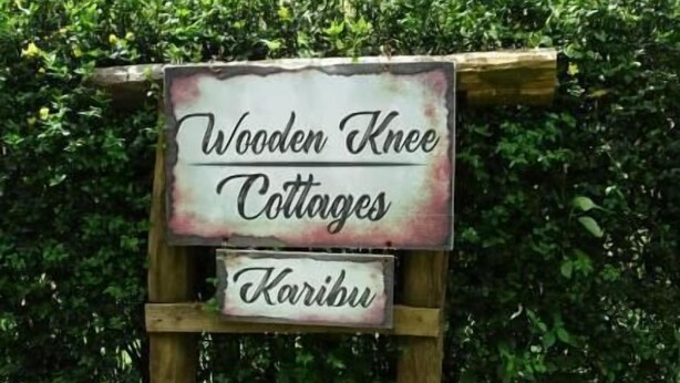 Une enseigne en bois pour le complexe de chalets « Wooden Knee Cottages », avec un design rustique.