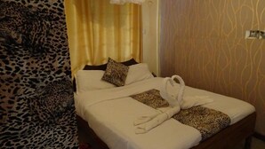 Une chambre d’hôtel avec un lit, un rideau à motifs léopard et un papier peint à motifs.