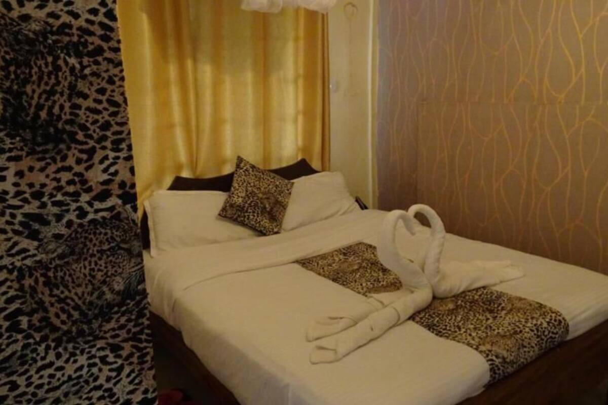 Ein Hotelzimmer mit einem Bett, einem Vorhang mit Leopardenmuster und einer Wand mit Muster.