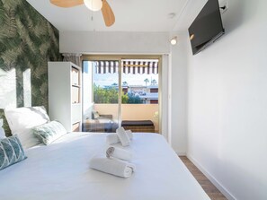 A hotel room with a bed, a ceiling fan, a TV mounted on the wall, and a view of the outside balcony. - 1-Br Apartment Near the Beach and the Croisette, Palm Beach (Cannes)