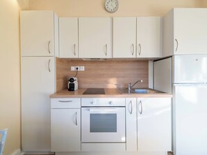 A compact kitchen with white cabinets, a built-in oven, a sink, and a coffee maker. - 1-Br Apartment Near the Beach and the Croisette, Palm Beach (Cannes)