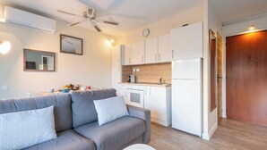 Un salón moderno con un sofá gris, una mesa de centro blanca y un ventilador de techo.
