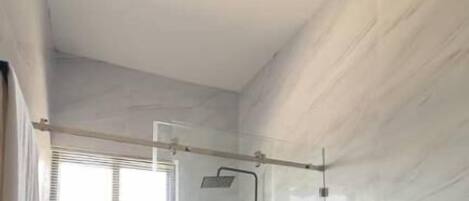 A modern bathroom with a glass-enclosed shower, a black toilet, and a unique ceiling light fixture.