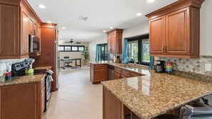 Una cocina amplia con encimeras de granito, armarios de madera y electrodomésticos de acero inoxidable.