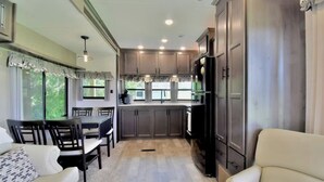 A modern kitchen with dark cabinets, a black refrigerator, and a dining area with a table and chairs.
