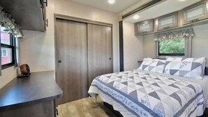 A bedroom with a bed, a dresser, a window with curtains, and a door.