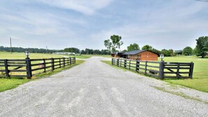 A gravel driveway leading to a rustic barn with a wooden fence on both sides. - Mins from the Lake! Camper King Bed • Firepit (Decatur)