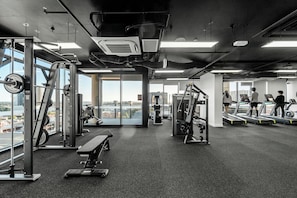 Een sportschool met trainingsapparatuur, loopbanden en een bank.