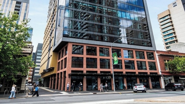 A tall, modern building with a glass facade and a mix of brick and metal elements at the base. - Luxe 1+1 Apt | Huge Balcony+BBQ  | Adelaide CBD (Adelaide)