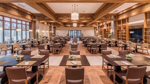 A spacious conference room with multiple tables and chairs, wooden beams on the ceiling, and large windows on one side. - Pujin Hotel (Jiaxing)