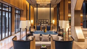A spacious lobby with a large chandelier, seating area with sofas and chairs, and large windows providing natural light. - Pujin Hotel (Jiaxing)