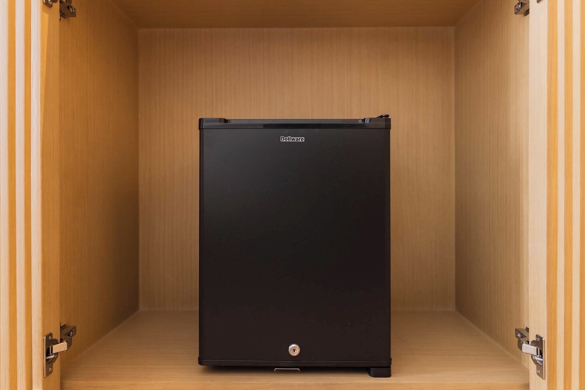 A black Dellware safe in a wooden cabinet with a lock.