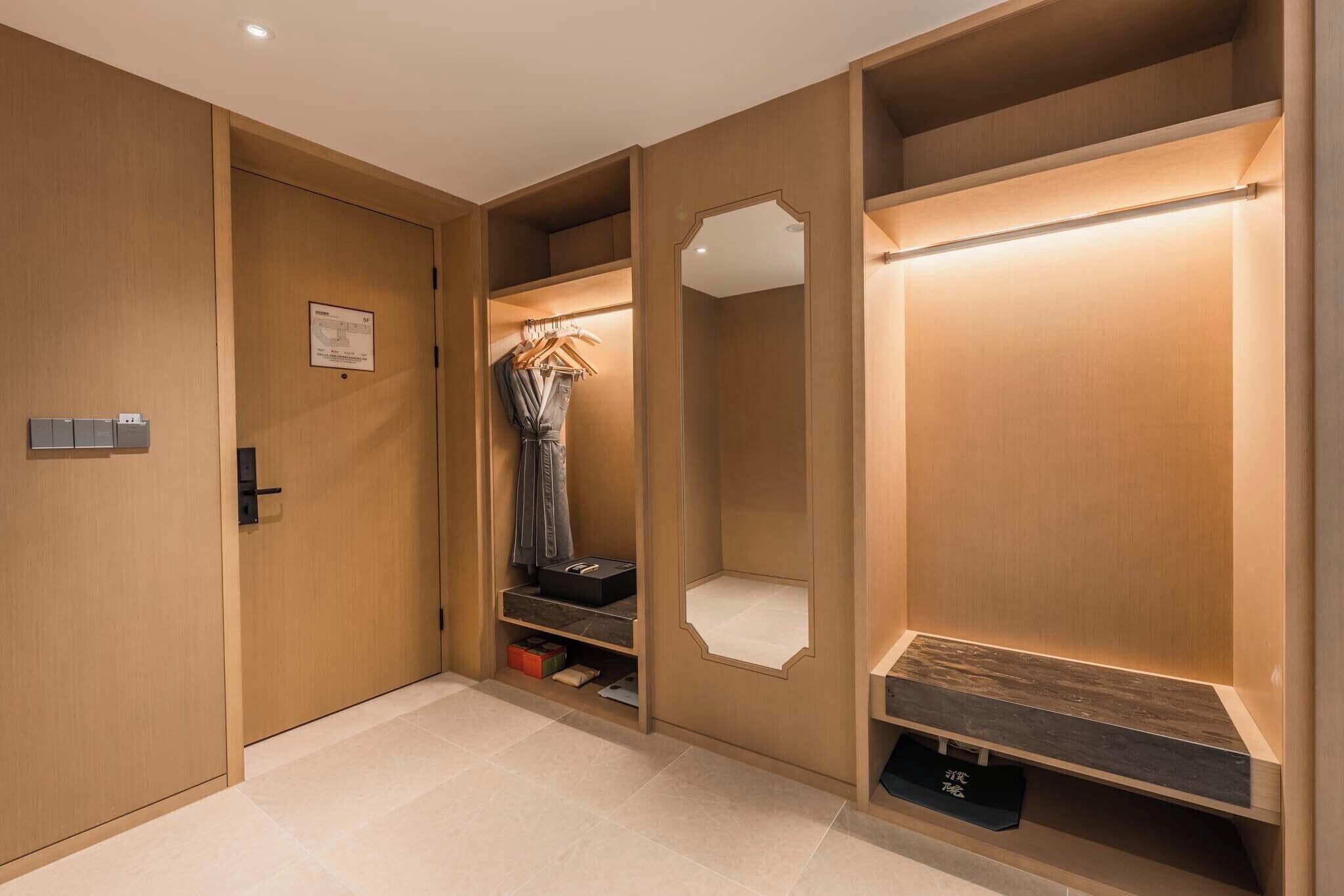 A walk-in closet with wooden doors, a hanging rack, shelves, and a mirror.