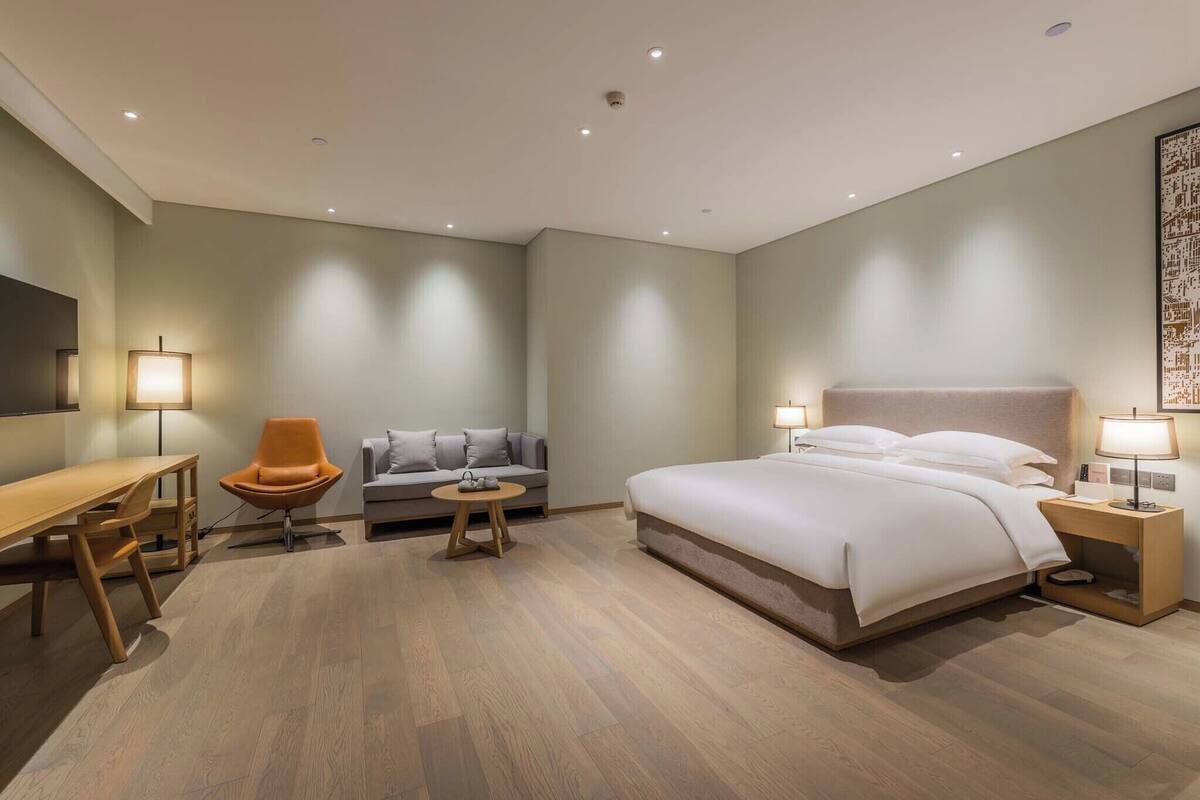 Una habitación de hotel moderna con una cama grande, un escritorio, un sofá y una mesita.