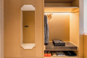 Un baño moderno y compacto con un mueble de tocador de madera, un perchero y una pequeña estantería con artículos de aseo.