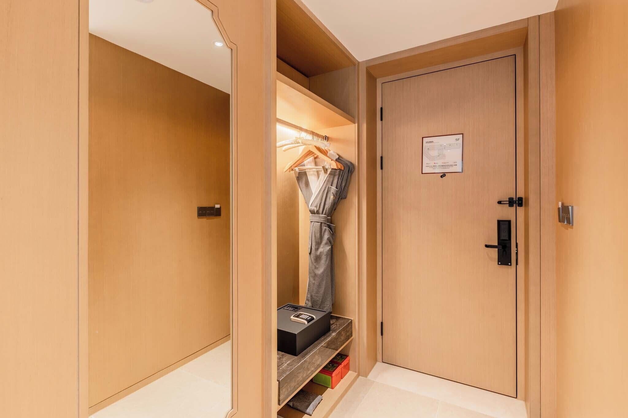 Habitación de hotel con armario de madera, perchero y puerta con lector de tarjeta.
