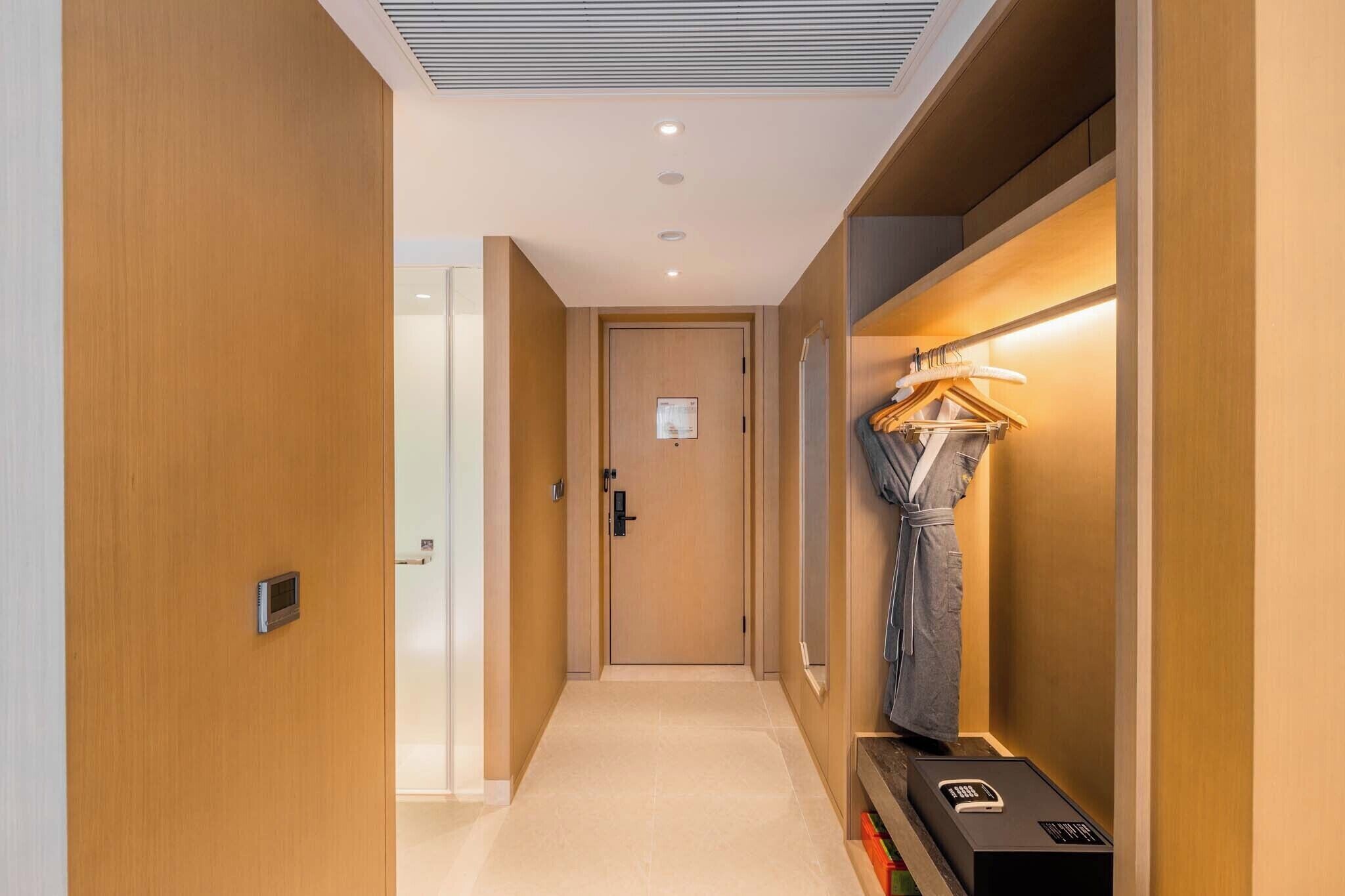 Un couloir aux murs en bois, une porte au fond et un portant à vêtements avec des cintres.